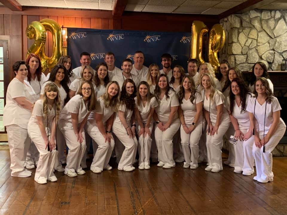 Group of nursing graduates in white scrubs.